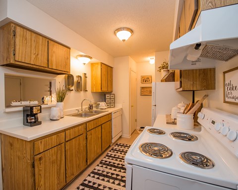 A kitchen with a white stove and wooden cabinets.