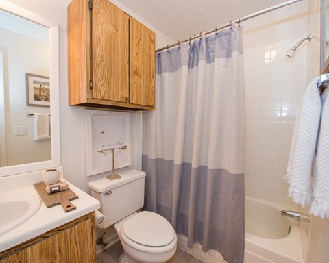 A white toilet sits under a shower curtain in a bathroom.