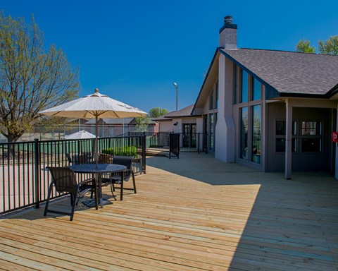 A wooden deck with a table and chairs and a patio umbrella.