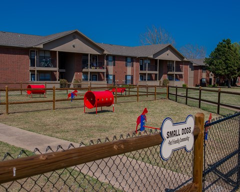 A playground area with a sign that says "Small Dogs" in front of a building.