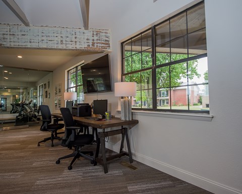 A room with a desk and chairs with a window in the background.