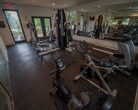A gym with a variety of equipment including treadmills, weights, and exercise machines.