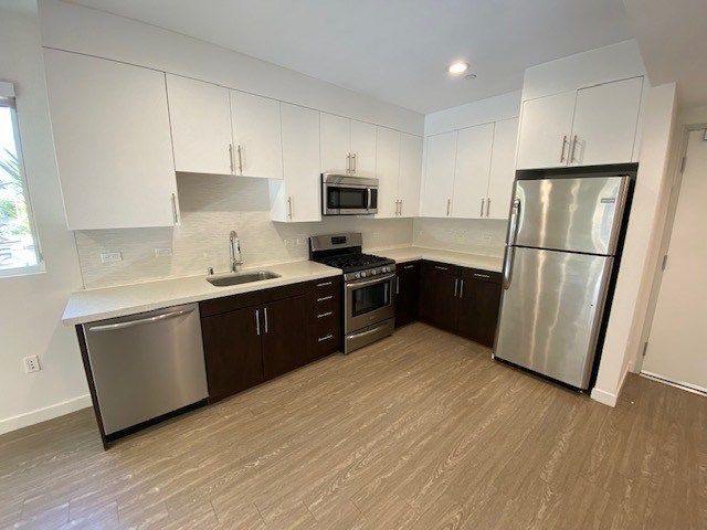 A kitchen with white cabinets, a refrigerator, gas stove, dishwasher and sink.