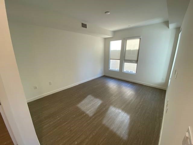 Bedroom with wood flooring and windows.