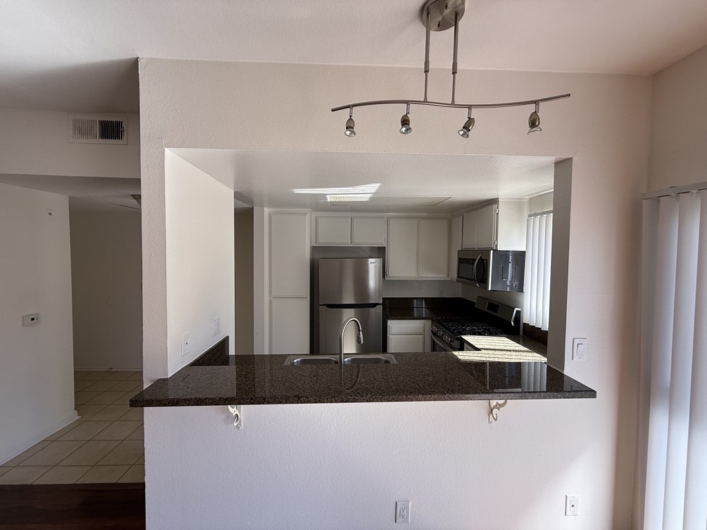 Kitchen with a refrigerator, microwave, gas stove and oven.
