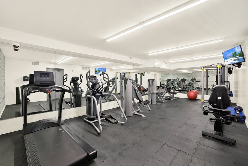 A gym with a variety of equipment including treadmills, weights, and exercise machines at Midvale Court, Los Angeles