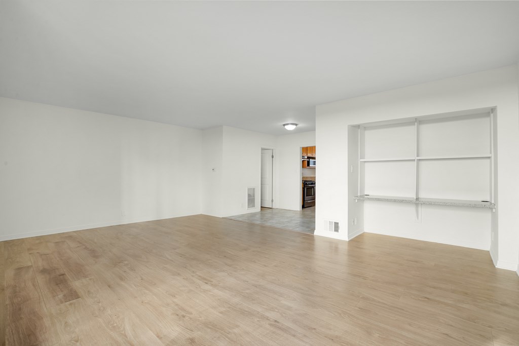 the living room and dining room of an empty house with white walls and wood floors