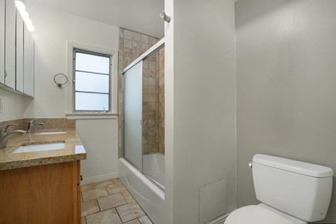 Apartment bathroom with vanity, toilet, and shower tub combo.