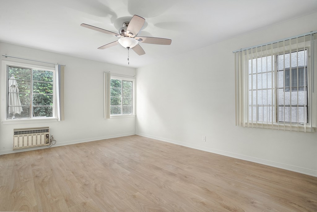 an empty room with a ceiling fan and two windows