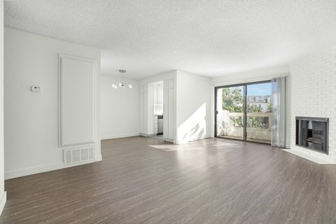 an empty living room with a wood floor and a fireplace