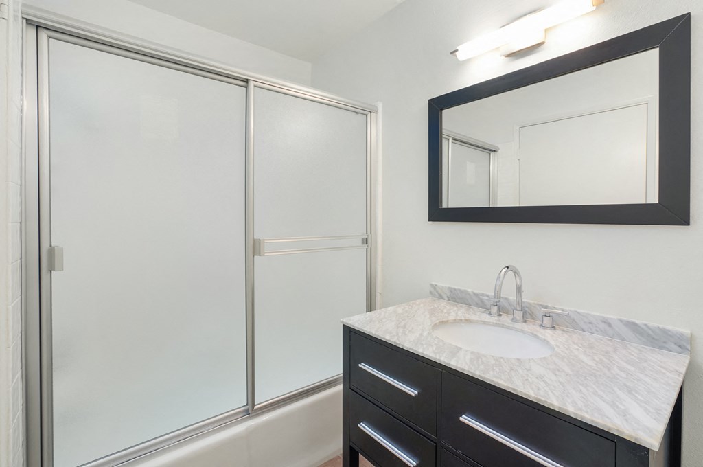 Apartment bathroom with vanity and shower tub combo.