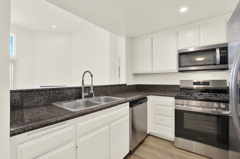 A modern kitchen with white cabinets and stainless steel appliances.