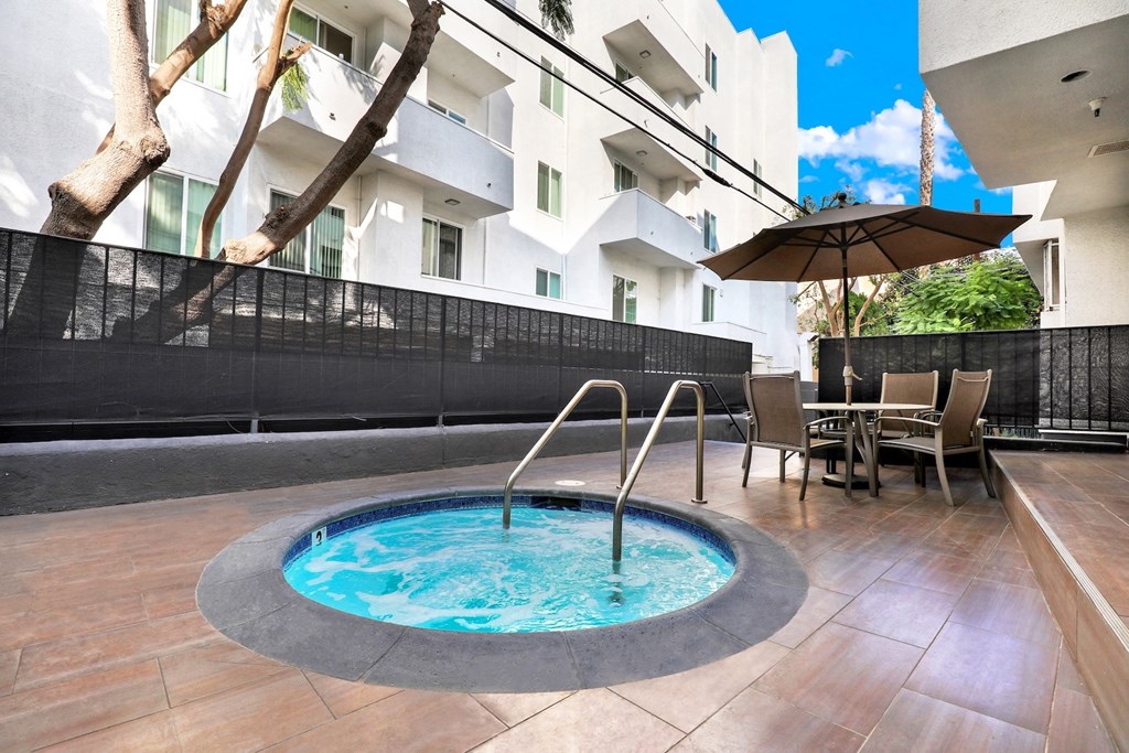 Spa in the middle of a patio with chairs and an umbrella at Park Rochester, Los Angeles, CA