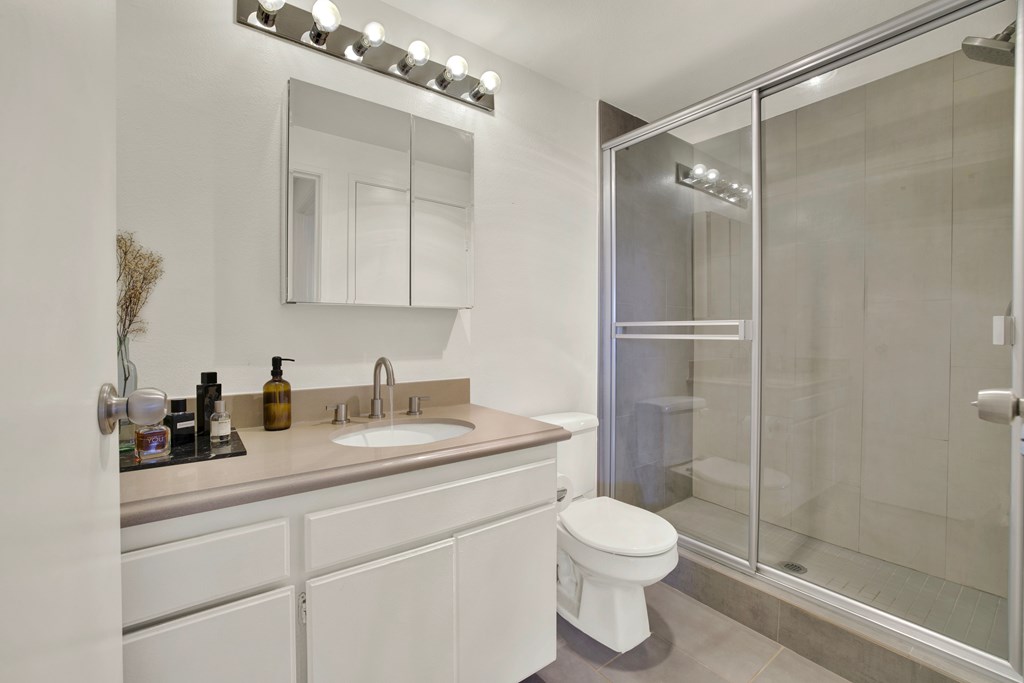 A white bathroom with a sink, mirror, and toilet.