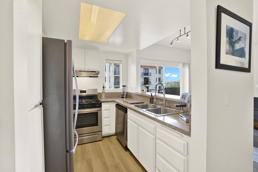 A kitchen with a refrigerator, sink, and cabinets.
