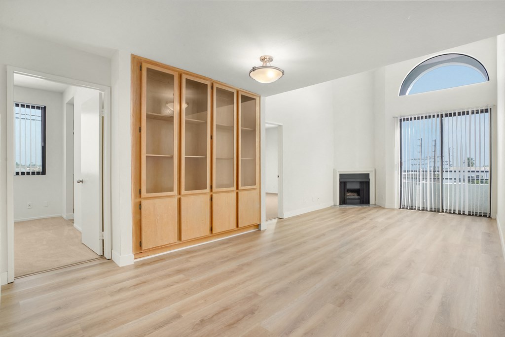 Apartment living room with a fireplace, built-in cabinets and balcony. at Midvale Court, Los Angeles, CA