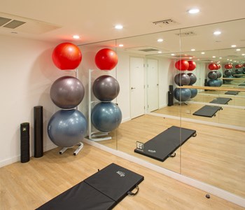 Apartment fitness center with a wall of mirrors, exercise balls, and a stretching mat.