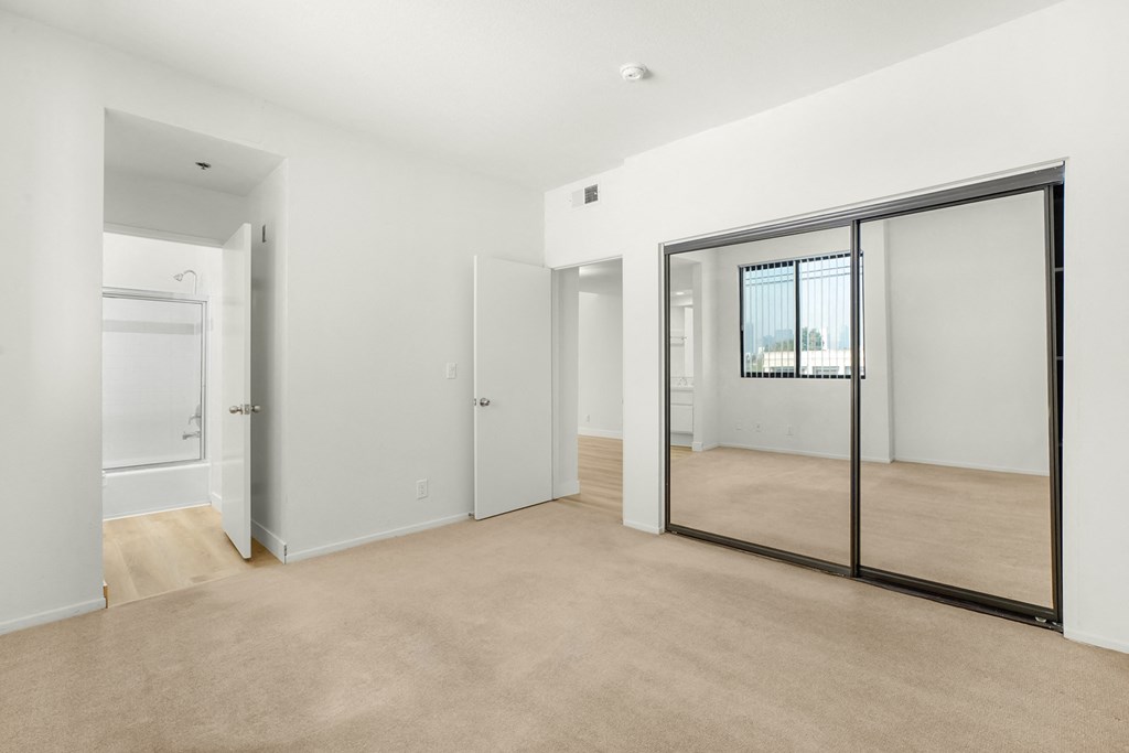Apartment bedroom with mirrored closet doors and an ensuite bathroom. at Midvale Court, California, 90024