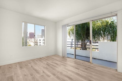 an empty living room with a sliding glass door and a balcony