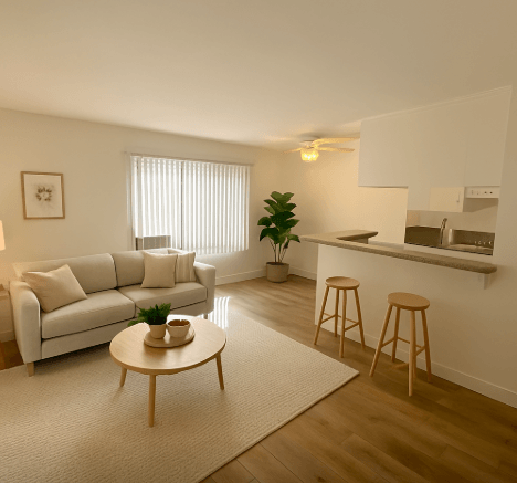 A living room with a white couch, a wooden coffee table, and a bar area with stools.