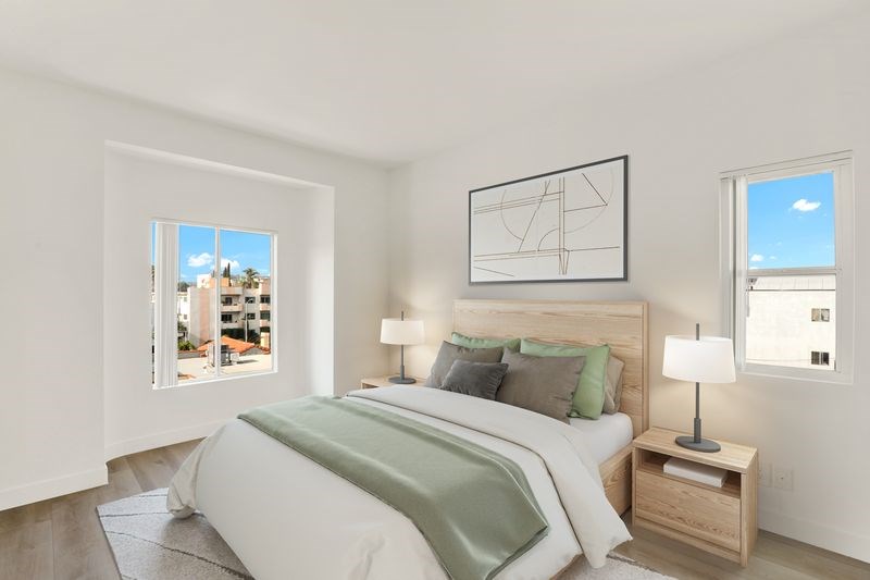 A bedroom with a large bed and a window overlooking a cityscape.