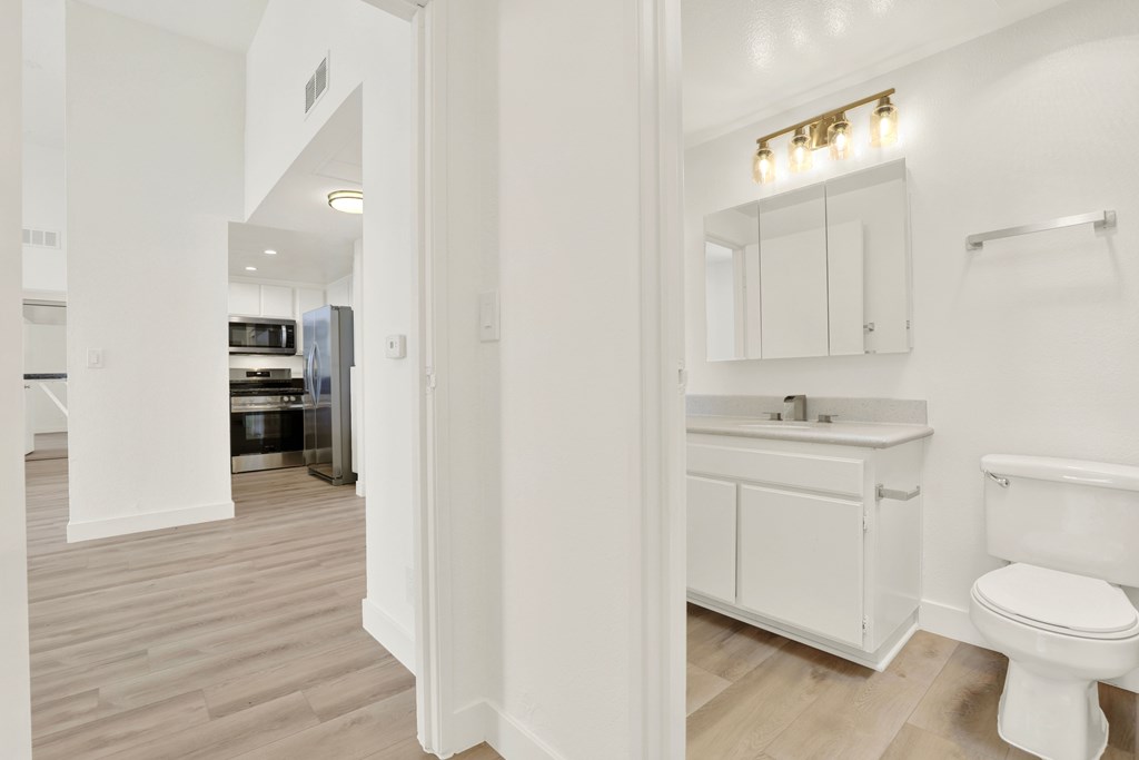 A white bathroom with a toilet, sink, and cabinet.