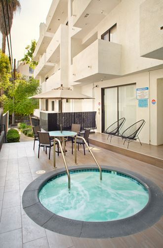 a hot tub with chairs and tables in front of an apartment building