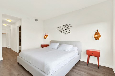 A bedroom with a white bed and a red stool.