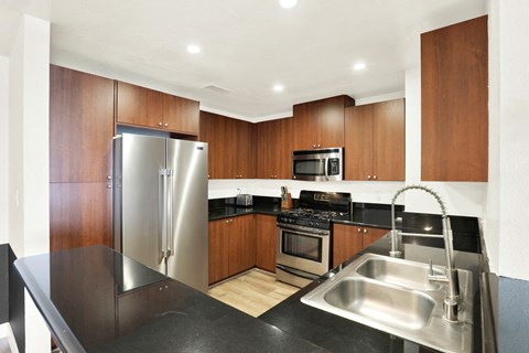 A modern kitchen with a stainless steel sink and refrigerator.