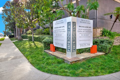 A sign in front of a building advertises a spacious luxury apartment at Twelve One Ten Rochester, Los Angeles, 90025