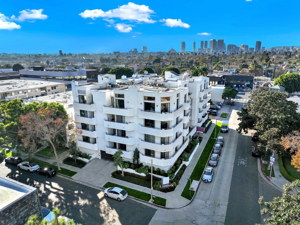 A white apartment building with a parking lot in front at Beverly Wooster Apartments, Los Angeles, California