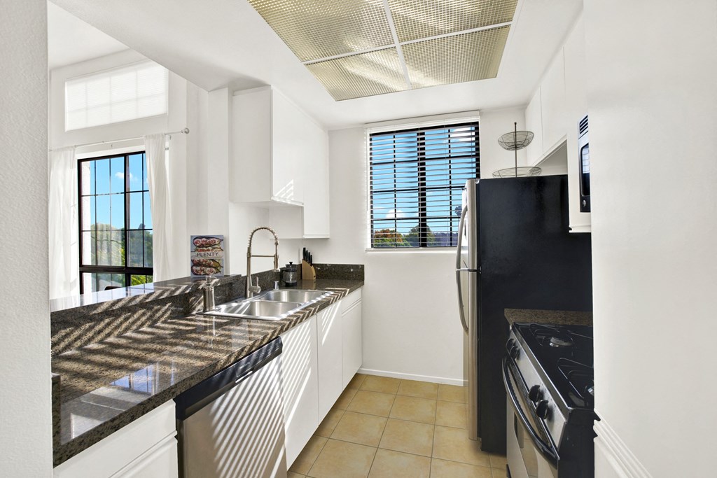 A modern kitchen with black granite countertops and white cabinets A modern kitchen with black granite countertops and white cabinets at Beverly Wooster Apartments, Los Angeles, CA