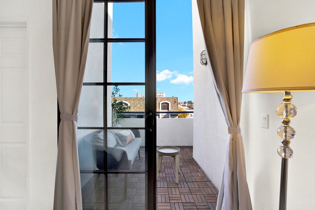 A room with a view of the city through a large window at Beverly Wooster Apartments, Los Angeles, California