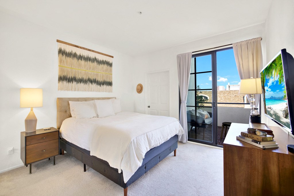 A bedroom with a large bed, a nightstand, and a television at Beverly Wooster Apartments, Los Angeles