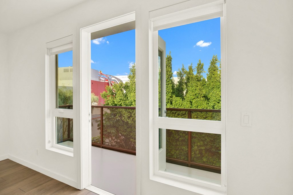 A room with two windows overlooking a red building and green trees at The Urbanpolitan, Los Angeles, CA 90036