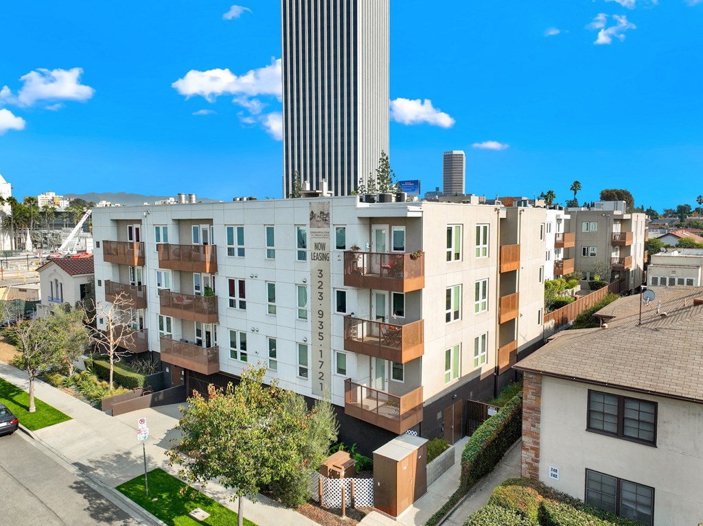 A tall building with a white facade stands in front of a row of houses at The Urbanpolitan, Los Angeles, California