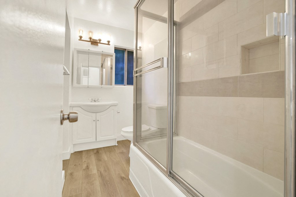 A white bathroom with a walk in shower at Wooster Encore Apartments, Los Angeles, CA