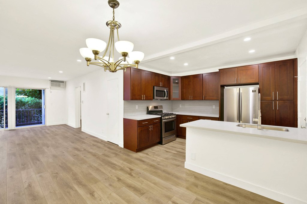 A modern kitchen with wooden cabinets and a white island at Wooster Encore Apartments, Los Angeles