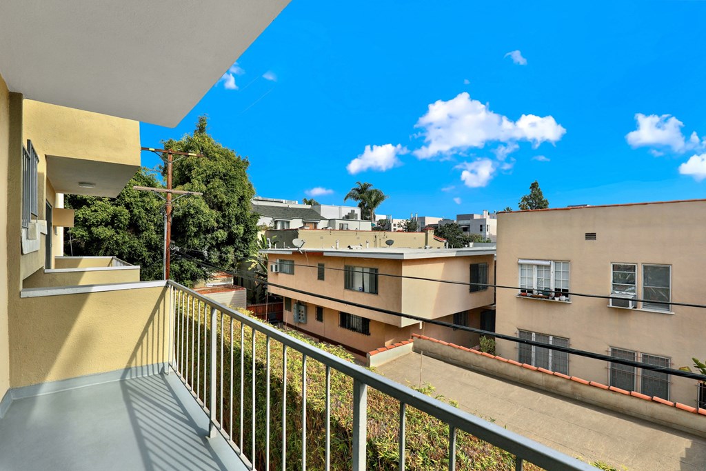 A balcony overlooks a courtyard with buildings and trees at Wooster Encore Apartments, California 90035