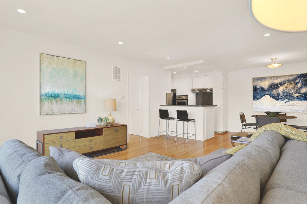 A living room with a grey couch and a painting on the wall at Wooster Encore Apartments, California 90035