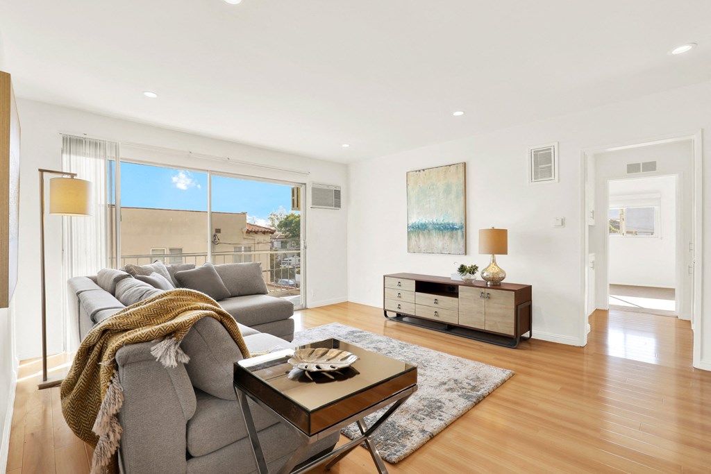 A modern living room with a grey sofa and a coffee table at Wooster Encore Apartments, Los Angeles, California