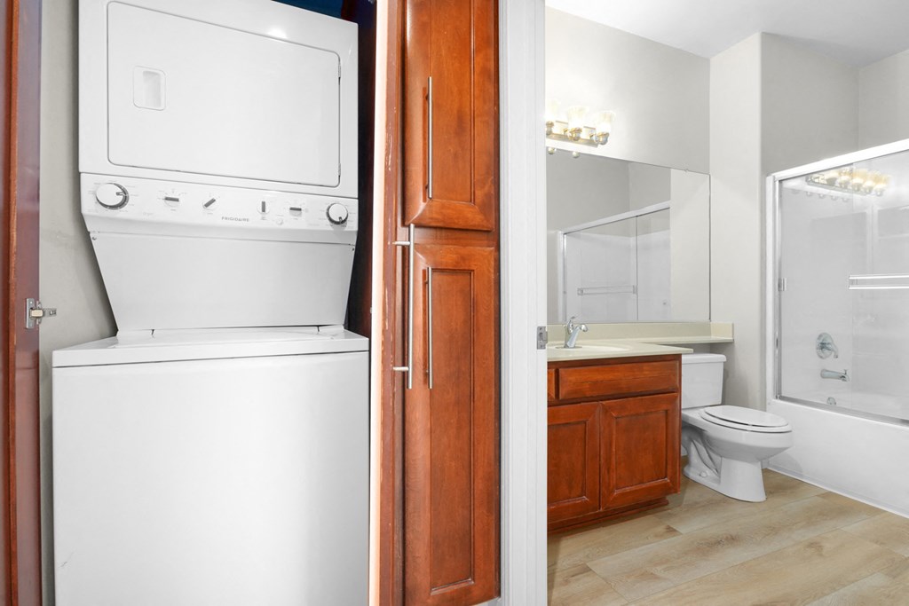Stacked laundry in hallway cabinet next to bathroom