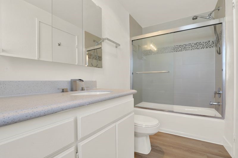 A white bathroom with a toilet, sink, and shower.