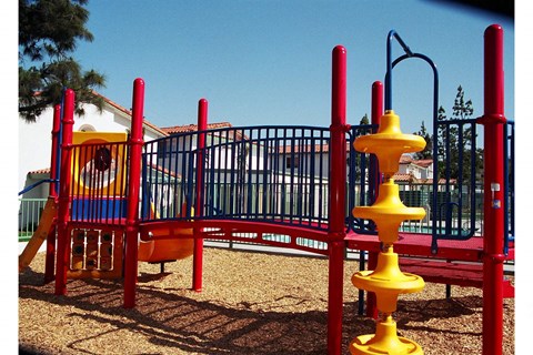 a playground with a red and yellow swing set