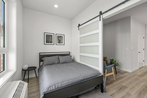 A bedroom with a large bed and a chair.