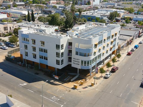 an aerial view of an apartment building with a parking lot and a street