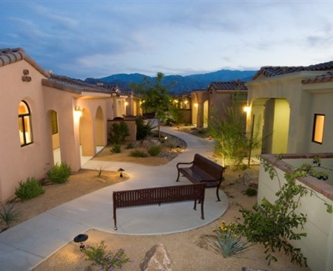 A courtyard with a bench and a wall with windows.