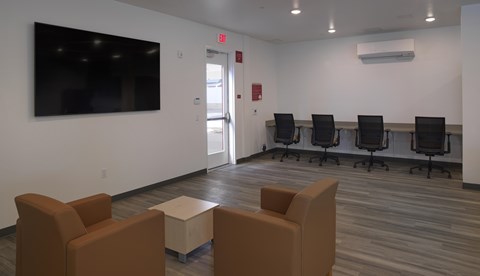 A conference room with a large screen, chairs, and a table.