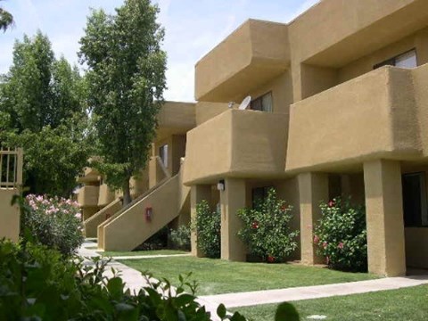 A building with a beige facade and a green lawn in front.