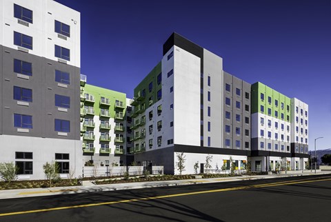 A row of modern buildings with green accents on the windows.